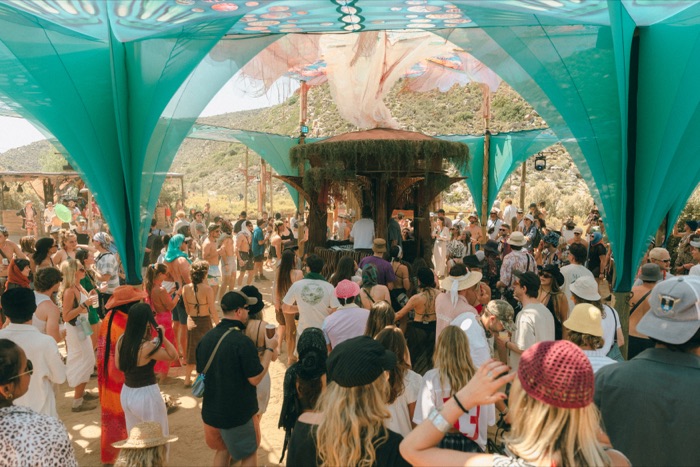 Teal petal canopy structure with crowd gathered below in daylight