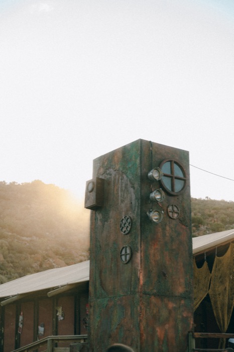 Rusted tower with porthole windows and spotlights at dusk