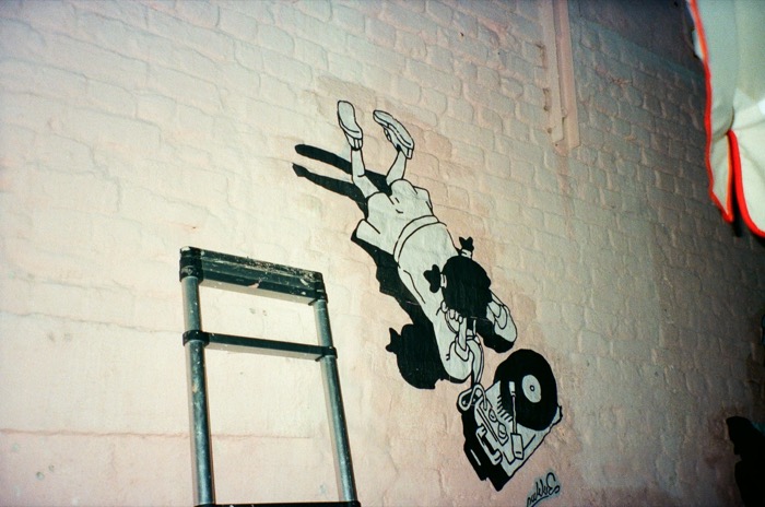 Diving DJ character wheatpaste piece beside a ladder