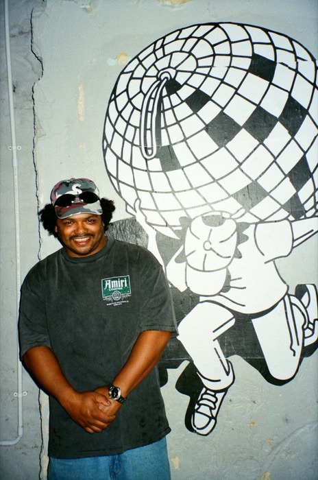 Portrait beside the wheatpaste Atlas-with-a-disco-ball mural